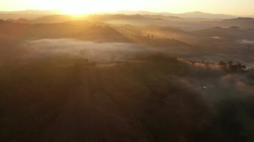 4K aerial view over a misty mountainous area. The great golden sun in the morning