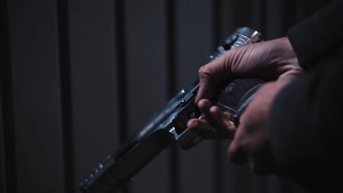 Adult Man Holding a Gun in His Hands and Pulls the Magazine Out of the Gun