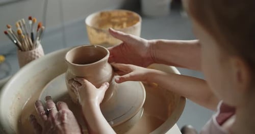 Adult and Child Making Pottery on Wheel