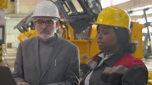 Multiethnic Engineer and Female Factory Worker Using Laptop
