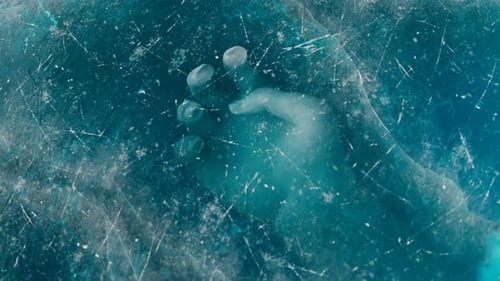 Une main humaine sous la glace. Le cadavre est piégé sous la glace.