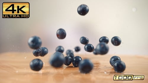 Fresh blueberries dropping onto a reflective surface