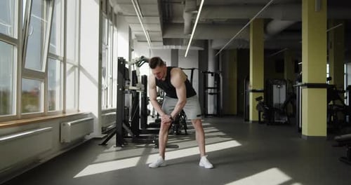 Young Muscular Athlete Works Out in a Modern Gym Making Warmup Exercises