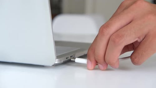 Close up hand inserting a USB cable charger into a computer.