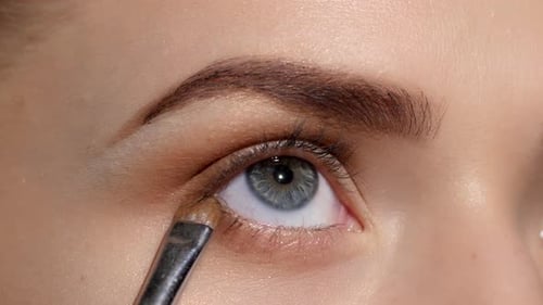 Aplicar maquillaje en el rostro femenino. Negra. Primer plano