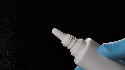 Spraying sanitizer from a white bottle against black