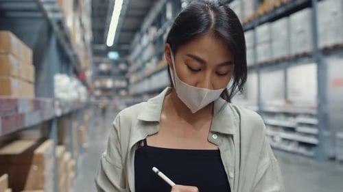 Young business woman wear mask using digital tablet check inventory levels in shopping center