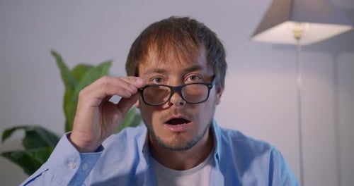 Man Removes Glasses and Looks Shocked Indoors