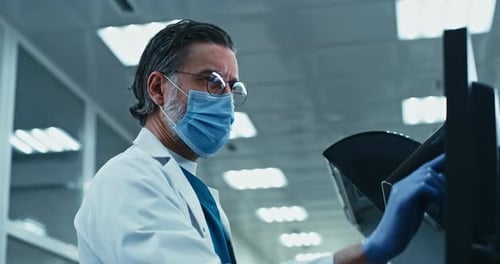 Doctor Working on Computer Wearing Mask and Gloves