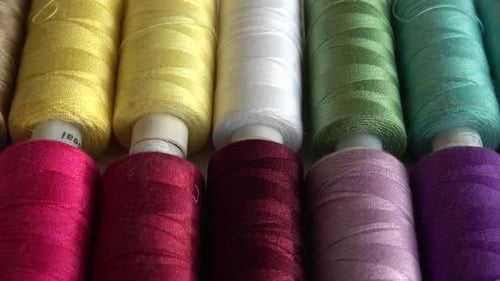 Top view of colorful thread spools isolated on white background.