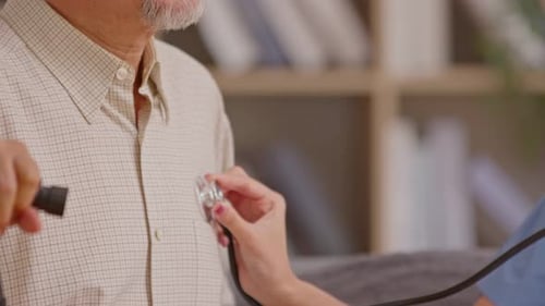 Close up Female doctor use stethoscope to examine elderly patient heartbeat. Caring female doctor us