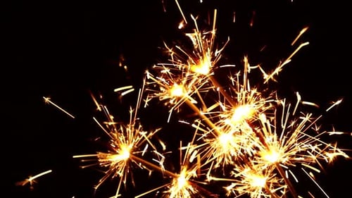 Burning Sparklers Create Bright Golden Sparks at Night