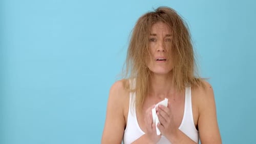 Woman Sneezing then Laughing in Front of Blue Backdrop