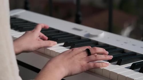 Hands Playing a White Keyboard in Sunlight