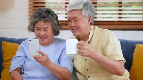 Senior Couple Smiles and Laughs Looking at Phone