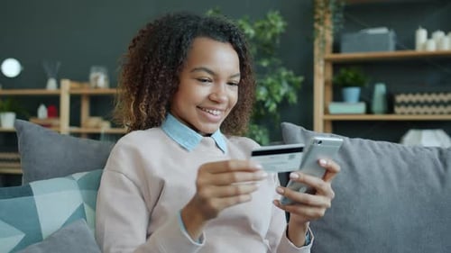 Smiling Woman Using Phone and Credit Card