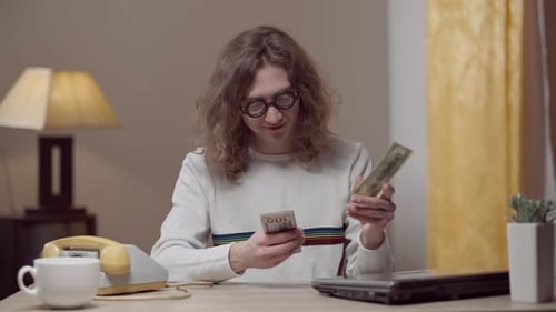 Adult Counts Dollar Bills at Desk