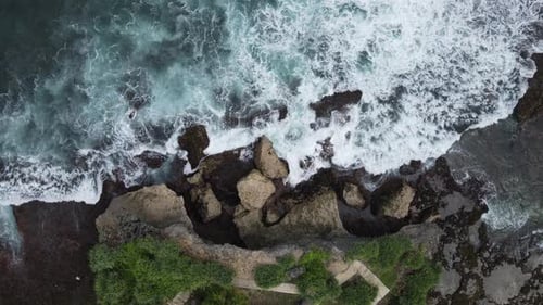 Top down aerial view of giant ocean waves crashing and foaming in coral beach