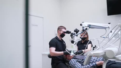 Dentist Working on Patient Using Microscope in Clinic