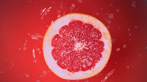 Medio pomelo fresco cayendo en jugo en cámara lenta