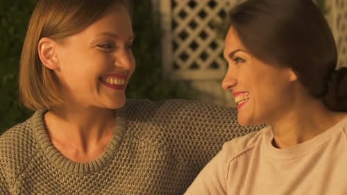 Smiling Women Embrace Affectionately at Night