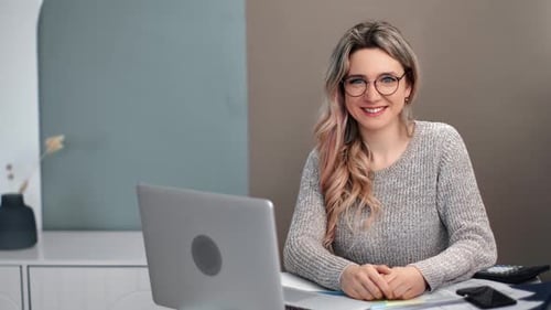 Cheerful Woman Smiling at Desk With Laptop