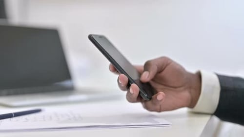 Close Up of Hands of African Man Using Smartphone in Office
