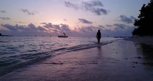 Beautiful smiling ladies on photoshoot in the sun at the beach on clean white sand and blue 4K backg
