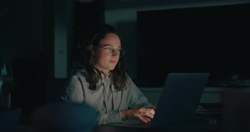 Young Woman Typing on Laptop at Night