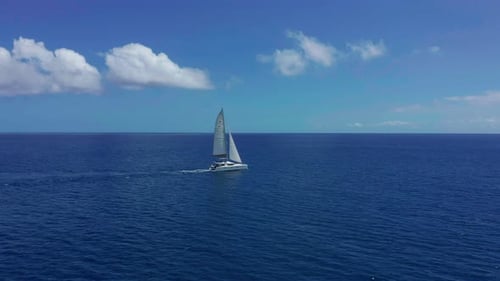 Aerial Footage Rear View of Luxury Sailboat Sailing on a Deep Blue Sea with White Wakes
