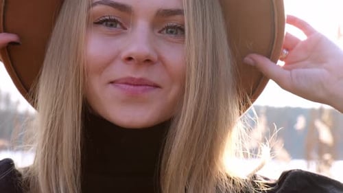 European Blonde Woman Smiling with Beige Hat in Black Sweater in the Countryside