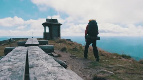 Tourist with Backpack on the Top of Mountain Spreads His Arms To the Sides