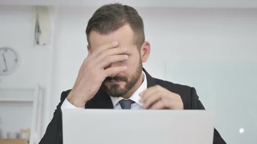 Stressed Businessman with Headache Working on Laptop
