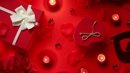 Romantic Gifts and Candles Arranged on Red Background