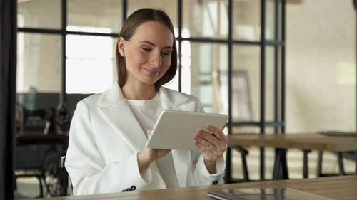 Focused Young Female Entrepreneur Using Her Digital Tablet While Sitting in the Office