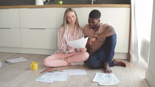 Couple Reviewing Financials on Kitchen Floor