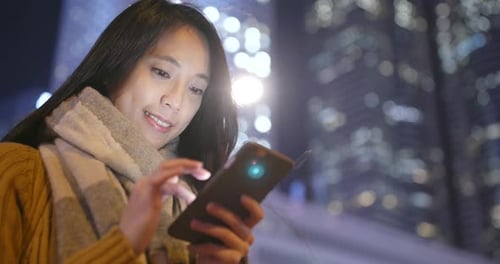 Woman use of smart phone in Hong Kong city at night