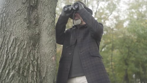 Man Observing with Binoculars in Park