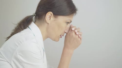 Close-up Side View of Exhausted Female Doctor with Head on Hands. Adult Brunette Caucasian Woman