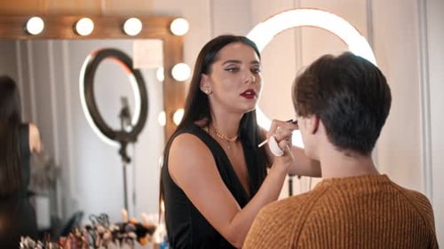 Woman Make Up Artist Applying Base on the Lids of Male Model Using a Brush