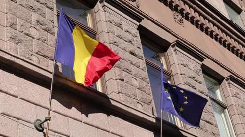 Romanian and European Union Flags Waving on Building