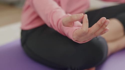 Gros plan sur les mains d'une belle femme caucasienne méditant en position de lotus en quarantaine à la maison.