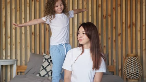 Preschooler Girl in Tshirt and Jeans Approaches Mother