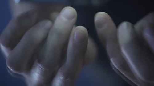 Männliche Finger, die Seiten verschieben und auf dem Smartphone tippen, Reflexion in Hochglanztabelle