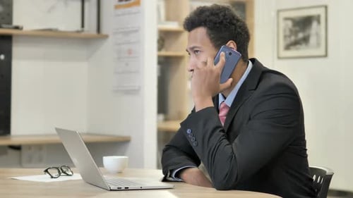 Man in Suit Talking on Phone at Desk
