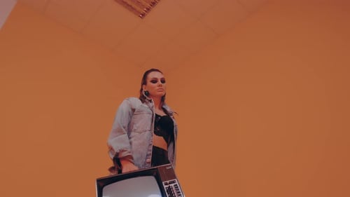 Woman Holding Retro TV in Orange Room