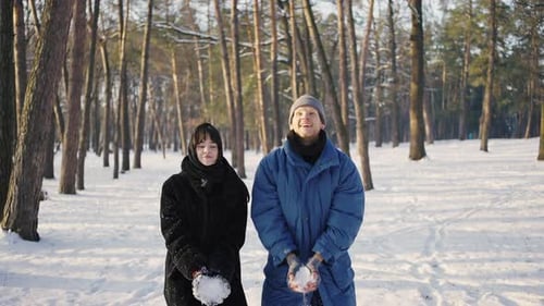 Jeune couple heureux jetant de la neige dans le parc d'hiver