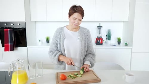 Woman Cuts Cucumber in Bright Kitchen for Healthy Snack