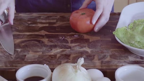 Trancher des légumes frais biologiques pour garnir un hamburger gastronomique