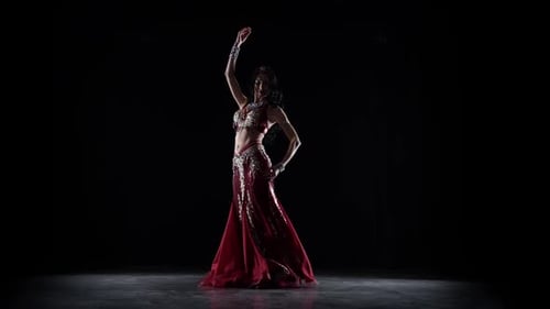 Belly Dancer Girl continue de danser dans une robe en chiffon. Fond noir